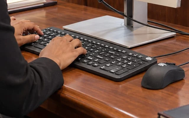 Close-up of MMI keyboard and mouse with the stenographer’s hands typing during courtroom proceedings