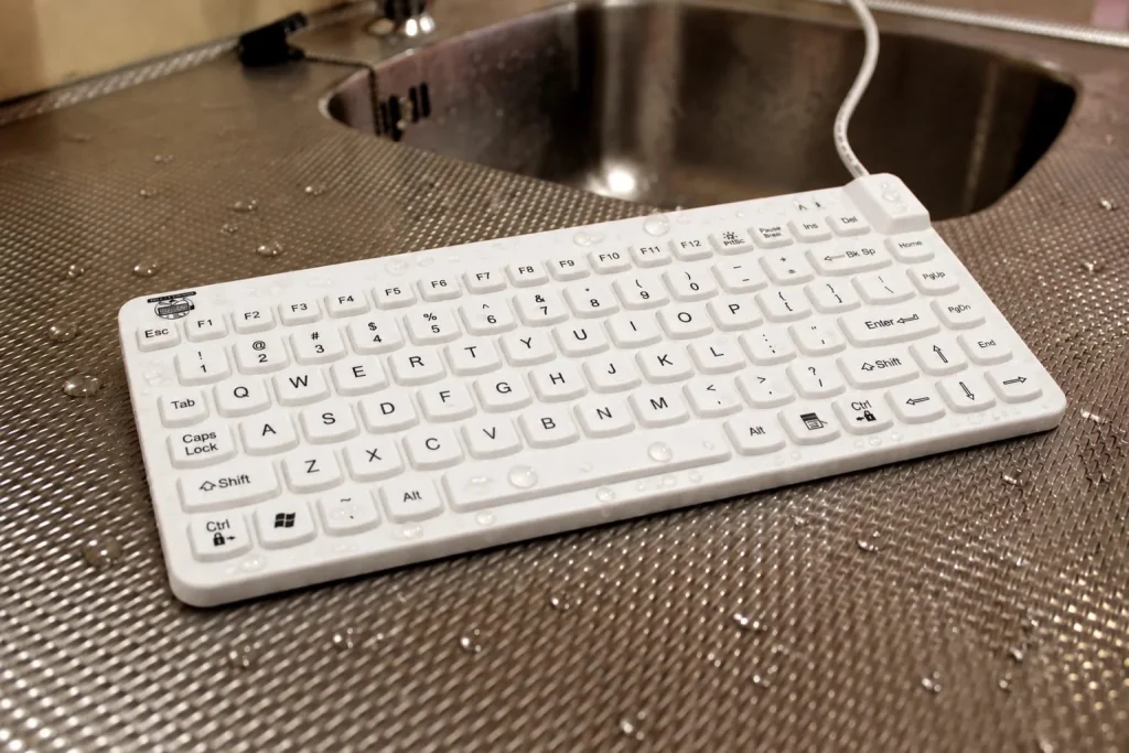 Wet MMI Slim Cool keyboard on a stainless-steel sterile processing workstation beside a sink