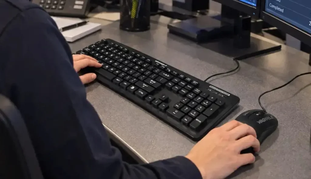 Close view of an emergency communications dispatcher using an MMI keyboard and mouse