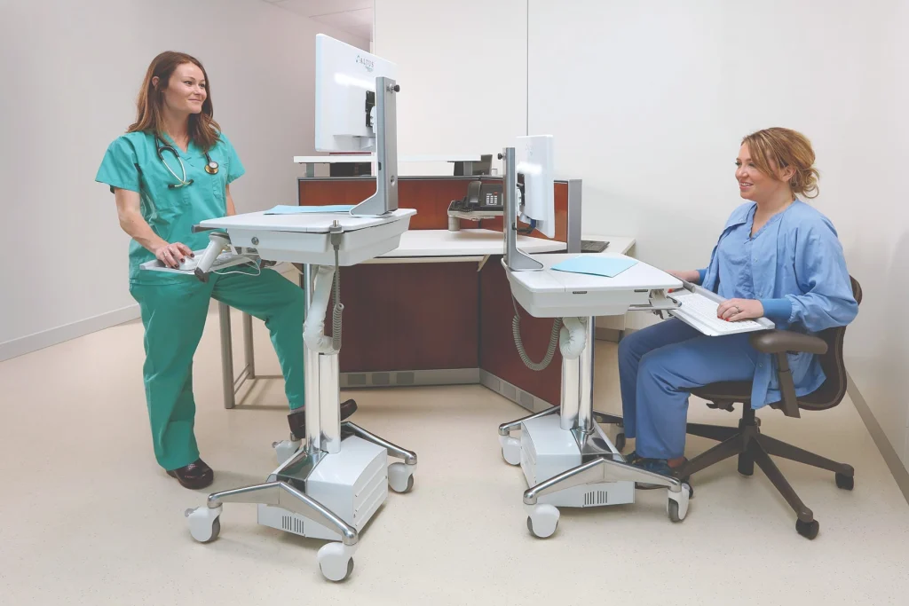 Two nurses using shared mobile clinical workstations