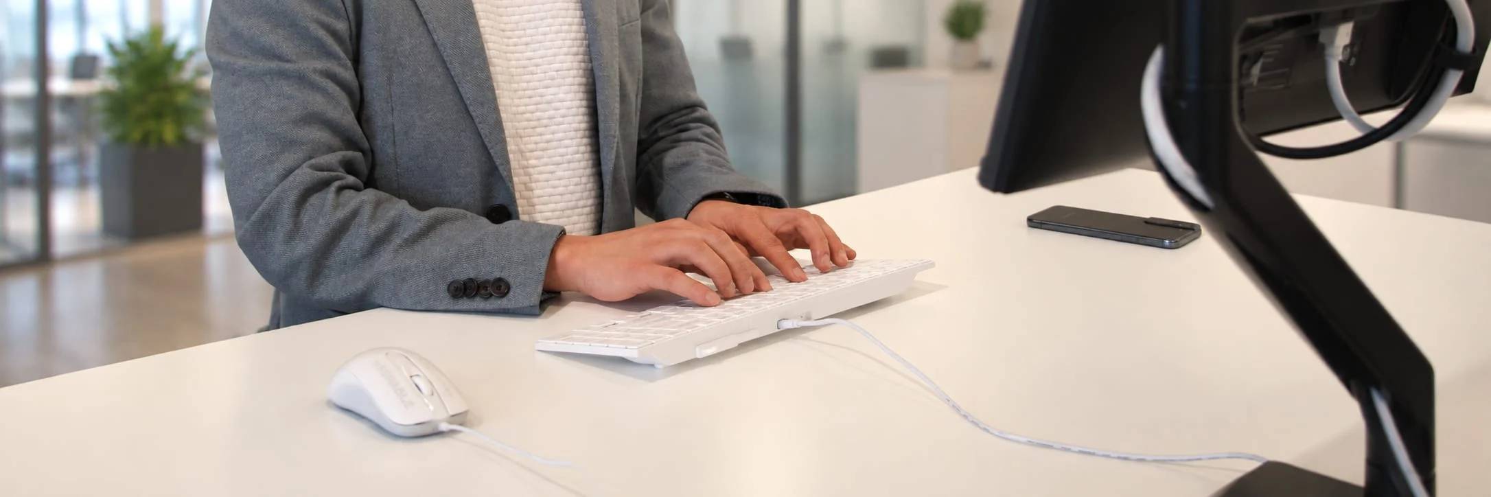 Professional using an MMI keyboard and mouse at a modern office workstation