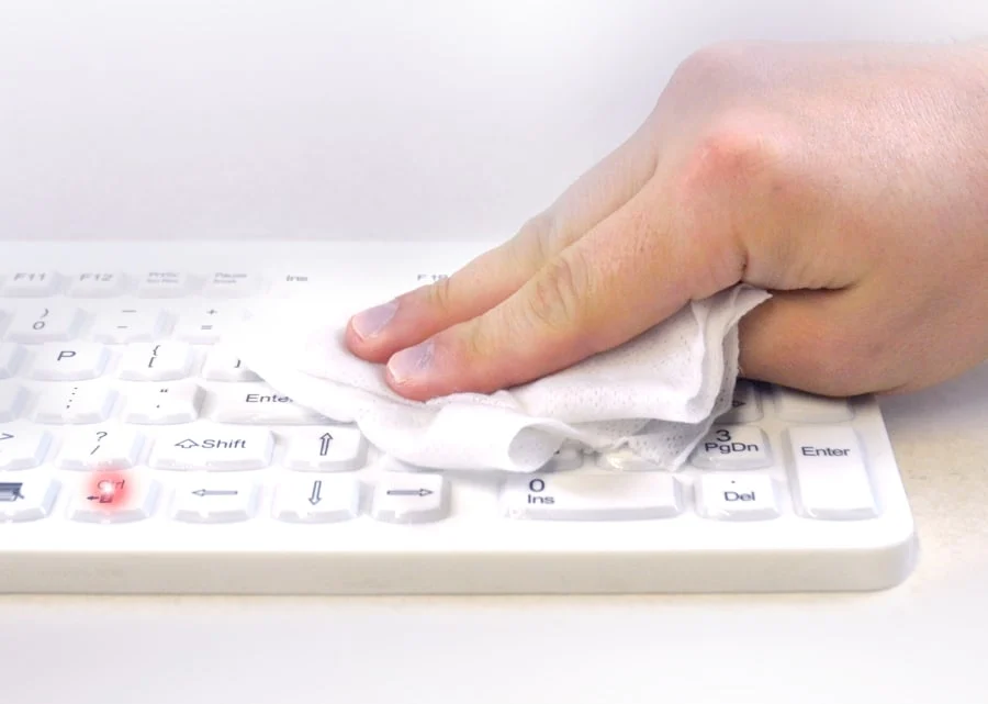 Hand wiping an MMI keyboard while its keys are locked for cleaning